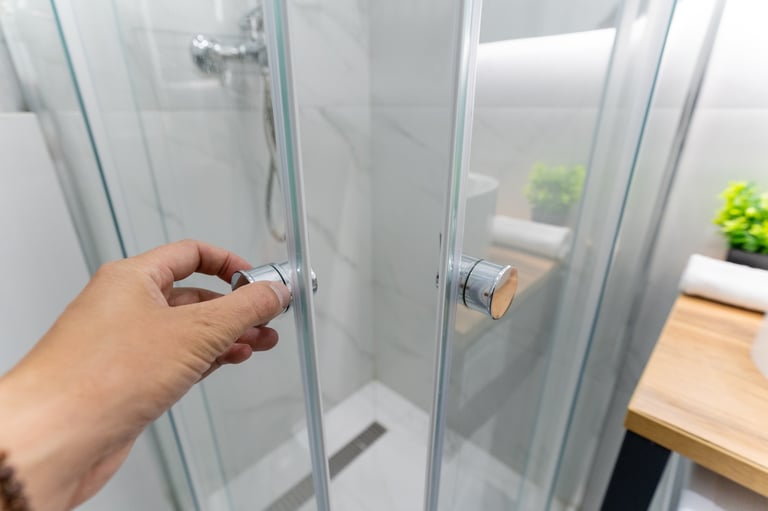 Person opening a sleek glass shower door in modern bathroom