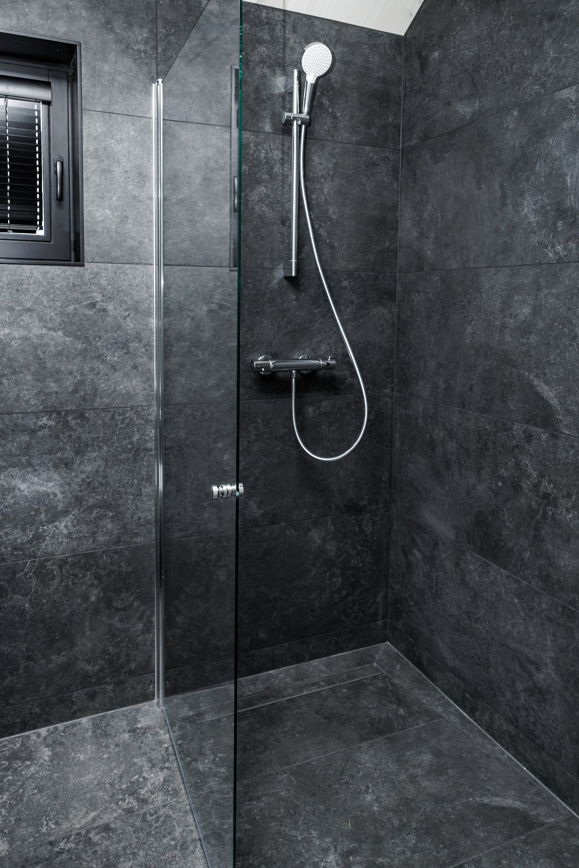 Modern sleek walk-in shower with chrome fixtures and glass partition