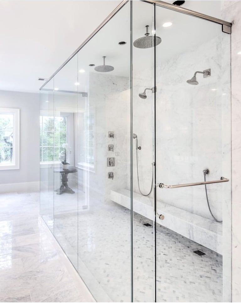 Modern luxury bathroom with large frameless glass shower enclosure featuring multiple showerheads and marble tile flooring