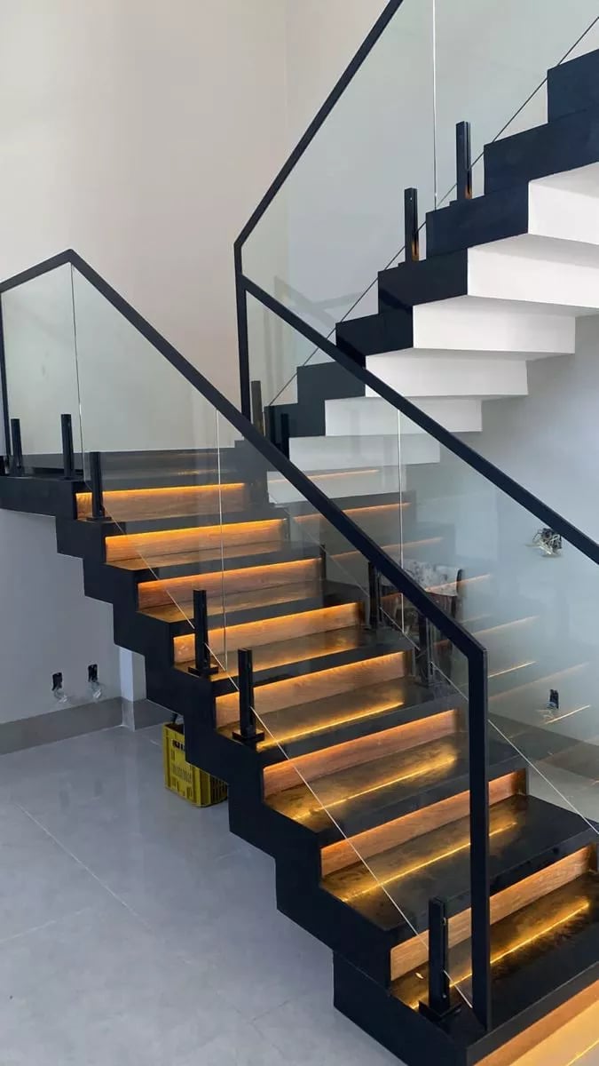 Modern staircase with black metal frame and glass railings with LED lighting